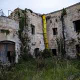Raggiungiamo infine le spalle della masseria. L�edificio da questo lato sembra ancor pi� decadente rispetto alla facciata: i vari ingressi del piano terra sono ostruiti da erbacce e le crepe nelle pareti rendono tutta la struttura pericolante